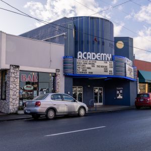 a blue theater with a car parked out front