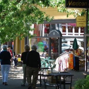 tables and shop items displayed on the sidewalk as people walk by on NW 23rd Avenue