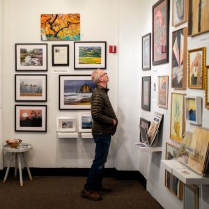 man looking at framed art hanging on art studio walls