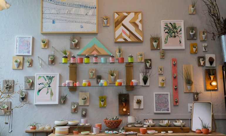 A wall of ceramic art and plants in a ceramic studio.