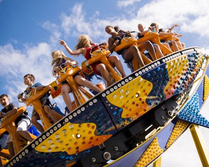 kids smile and spin on a colorful amusement ride on a sunny day