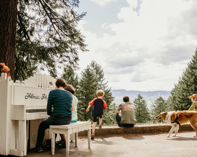 family at mount tabor park plays piano and looks at view with dogs