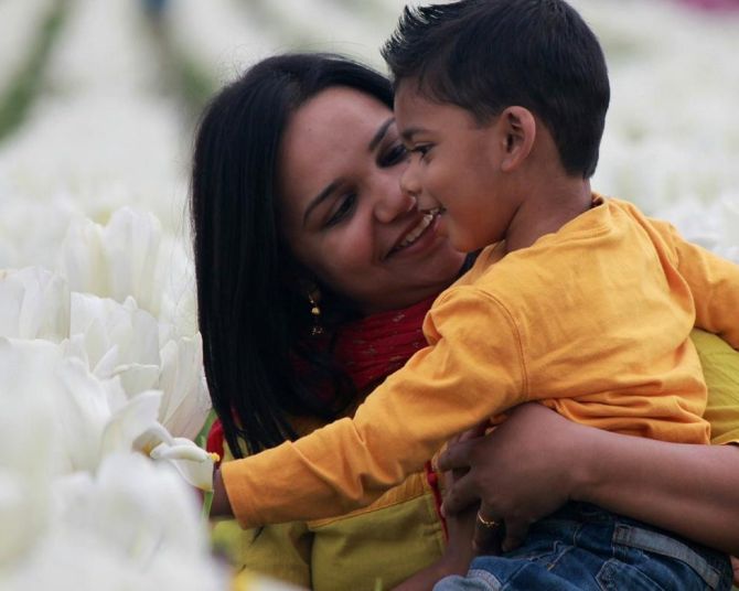 a mother holding her child in the middle of rows of white tulips