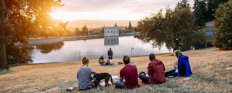 people enjoy a picnic at sunset looking out over a reservoir
