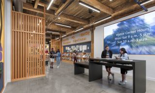 People walking the entryway at the Portland Visitor Center, reading brochures and socializing.