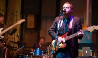 a band with electric guitar, bass and drums performing live music