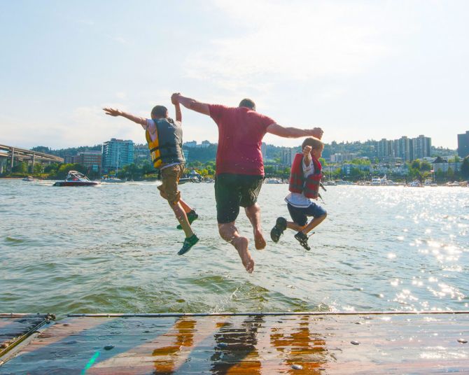 three people mid-jump into a river