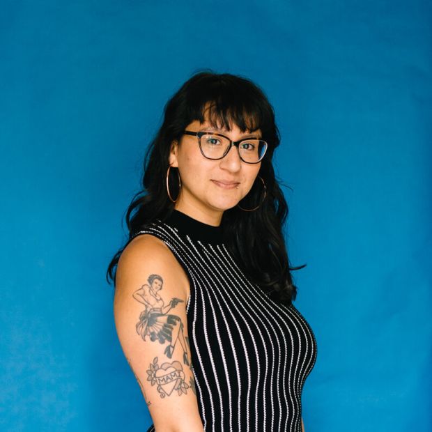 image of a person wearing glasses in a striped shirt standing in front of a blue backdrop