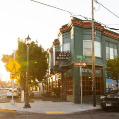 a green building at a street corner bathed in sunlight