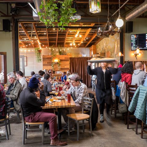 people seated at tables eating inside a brewery