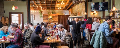 people seated at tables eating inside a brewery