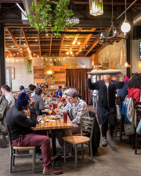 people seated at tables eating inside a brewery