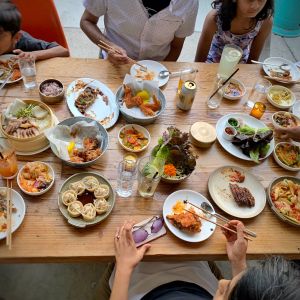 people sit around a vast spread of Korean food arrayed on a wooden table