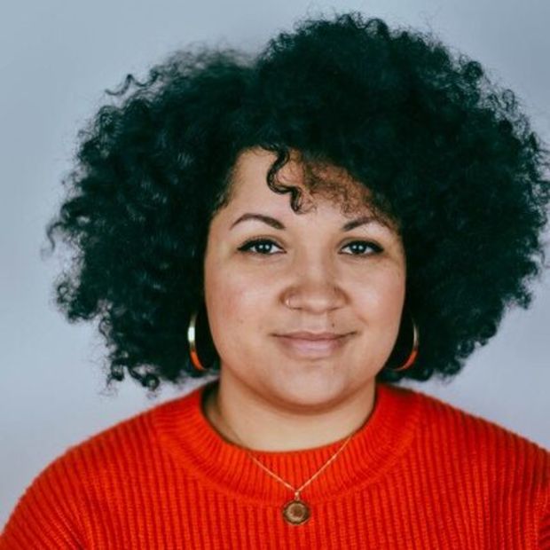 image of a person smiling with a red sweater and curly hair