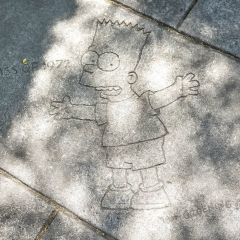 a depiction of cartoon character Bart Simpson on a sidewalk