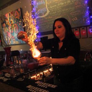 a bartender making a flaming drink behind the bar at Local Lounge