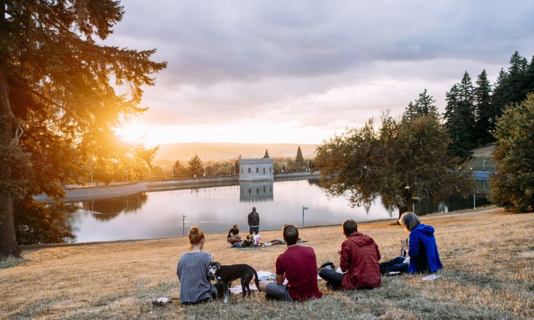 people enjoy a picnic at sunset looking out over a reservoir