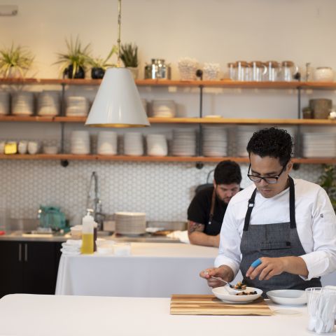 A chef plates some food in a kitchen