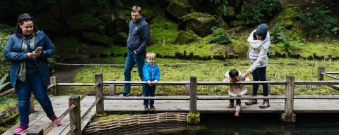 three adults and two children view koi fish in a pond
