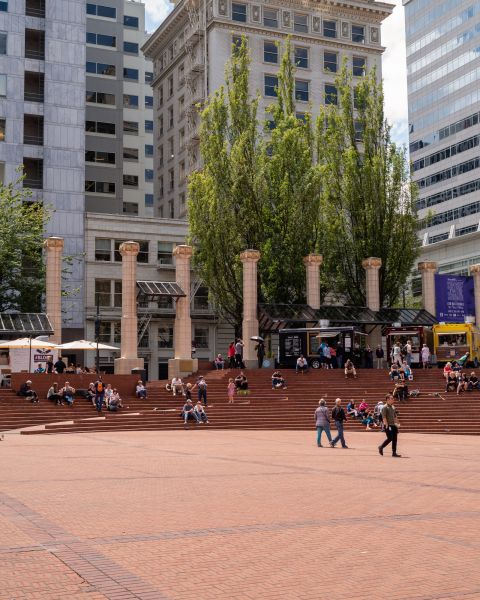 people sitting, walking in brick plaza with white columns