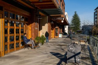 walkway with storefronts and people sitting at tables outside in the bright sunlight