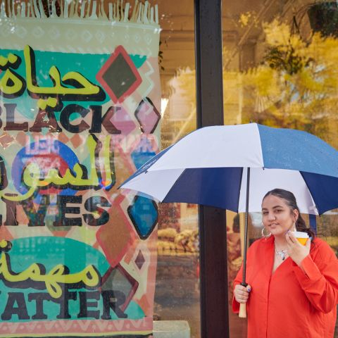 a woman holding an umbrella and coffee cup