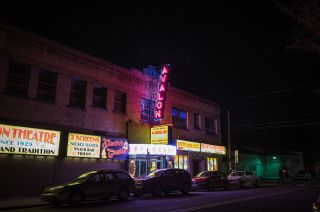 nighttime street view of neon signs adorning a historic neighborhood theater and arcade
