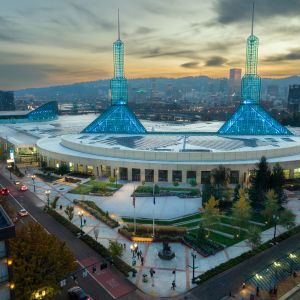 a vast building with two spires at sunset with the city skyline and hills in the background