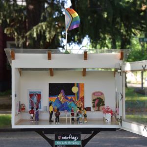 small white box with tiny art gallery diorama is displayed on a neighborhood street