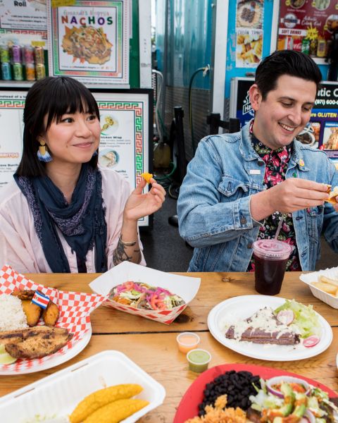 two people enjoying food at a food cart pod