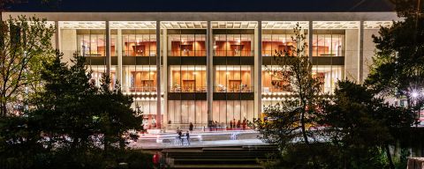 exterior of the Keller Auditorium at night showing a wide building lit from within, viewed from the Keller Fountain, whose geometric lines mirror the auditorium\'s architecture