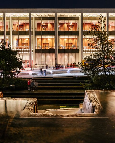 exterior of the Keller Auditorium at night showing a wide building lit from within, viewed from the Keller Fountain, whose geometric lines mirror the auditorium\'s architecture