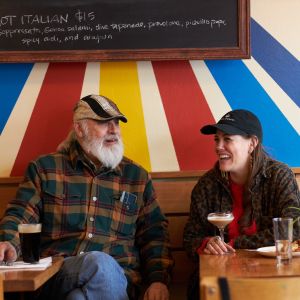 Two people sit and laugh with food and drink in a restaurant