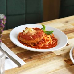 vegan chicken parmesan sits next to a pizza on a wood table