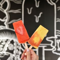 a woman\'s hand holds up two sweet popsicles