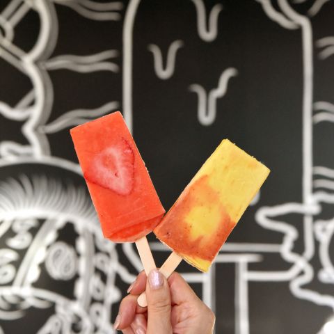 a woman\'s hand holds up two sweet popsicles