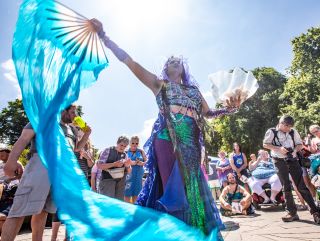 a dancer performs with fans and long pieces of cloth in front of a crowd