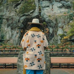 Someone stands in front of a rock wall.