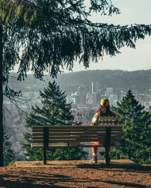 a person sits on a bench overlooking Portland at Mount Tabor Park
