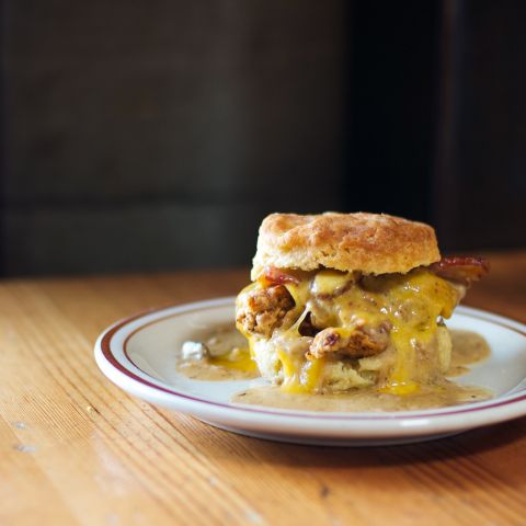 A biscuit sandwich with egg, sausage and melted cheese on a plate
