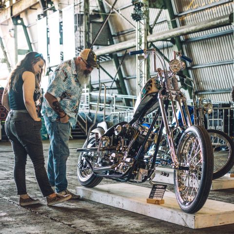 a man and a woman look at a custom motorcycle on display