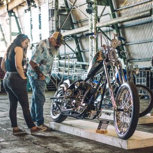 a man and a woman look at a custom motorcycle on display