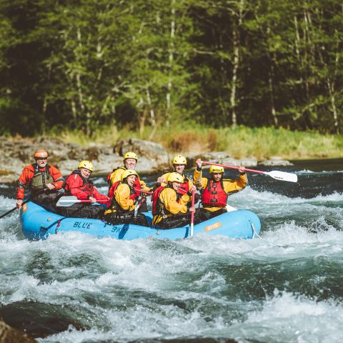 people in a blue raft ride the rapids on a rive