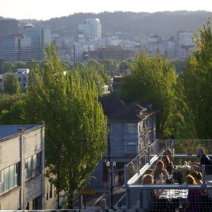 Dinners enjoying the last rays of sun on the rooftop deck at Noble Rot restaurant with sweeping views of downtown in the background.