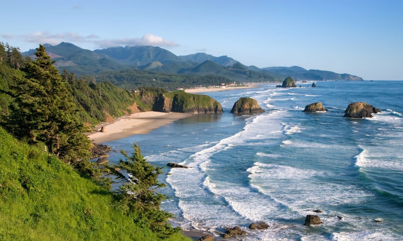 view overlooking Ecola Point, ocean waves crashing on the beach wit h large rock formations