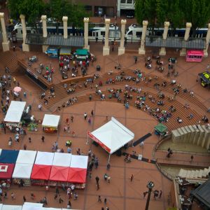 Aerial view of downtown\'s Pioneer Courthouse Square filled with people, concessions and a stage for live music.