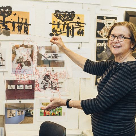 an artists lifts up a piece of artwork