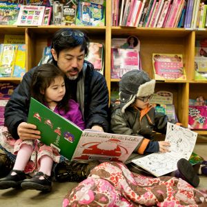 A family sitting on the floor reading children’s books at Powell’s City of Books.