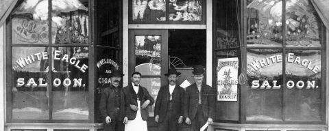 a black and white photo of three men standing in front of a saloon