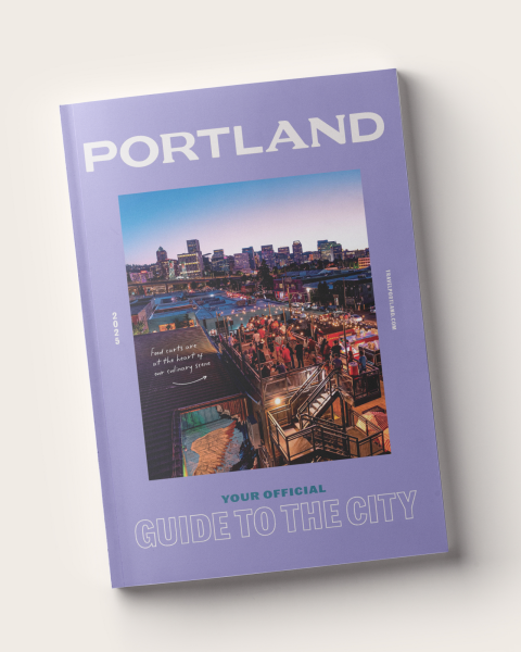 a copy of the Travel Portland Visitor Guide which features an image of Portland surrounded by a purple frame and the words \"Portland your official guide to the city\"